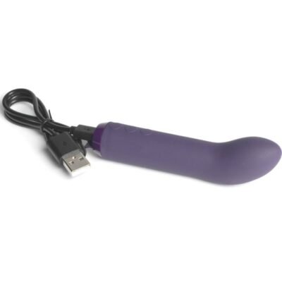 Vibrador roxo acinzentado com a ponta curva. Aparelho está apoiado e pode-se ver o cabo de carregamento USB.