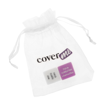 Saco de tecido branco com a inscrição 'cover me' e dois dados: um branco com 'neck, cuello, cou' e um rosa com 'tickle, cosquillas, chatouilles'. Cada dado mostra palavras em três idiomas (inglês, espanhol e francês) indicando áreas do corpo e ações.